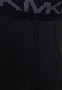 Shorts de sport noirs à texture lisse, dotés d'une large taille élastique gris foncé avec détail de logo et couture flatlock.