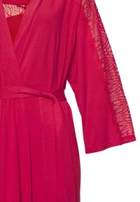 Ružičasta haljina do koljena s dizajnom omotanja, izrađena od mekane tkanine. Dugi rukavi imaju čipkaste detalje duž rubova. Veže se u struku.