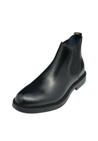 Stivale Chelsea in pelle nera con pannelli laterali elasticizzati, punta arrotondata e tacco rettangolare basso. Superficie liscia e dettagli di cucitura minimi.