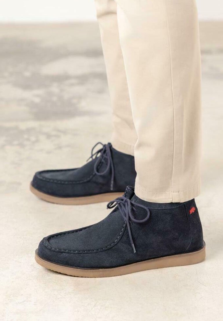 Botas de tobillo de ante azul marino oscuro con suela de goma marrón, que presentan detalles de costura y un acento del logo de conejo cerca del talón.