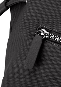 Schwarze Stofftasche mit strukturiertem Äußeren, einem sichtbaren Reißverschluss mit metallischen Beschlägen und einem rechteckigen Reißverschlussanhänger.