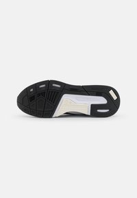 Suola di sneaker in gomma nera con motivi testurizzati, dettagli argentati e sezioni bianche per supporto. Presenta scanalature per la trazione.