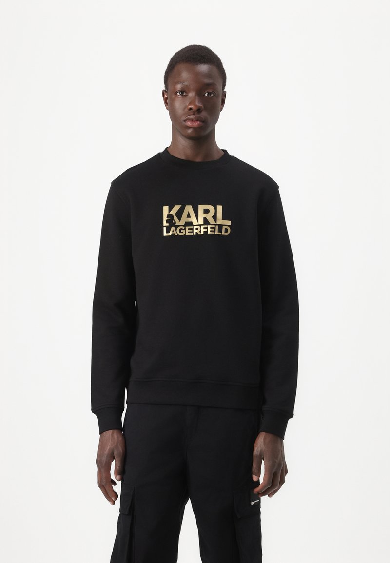 Sudadera negra con escote redondo, que presenta un gran texto en dorado "KARL LAGERFELD" en el pecho. Fabricada en tejido suave.