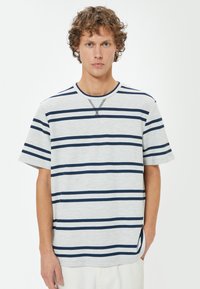 Randig kortärmad t-shirt i ljusgrått med mörkblå horisontella ränder. Har rund halsringning och subtilt strukturerad detalj vid halsen.