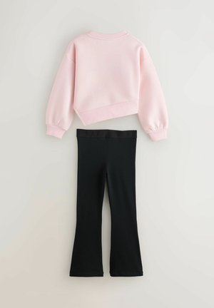 Lyserød cropped sweatshirt med lange ærmer, parret med sorte flared leggings med en sort elastisk talje med "BAKE" bogstaver.