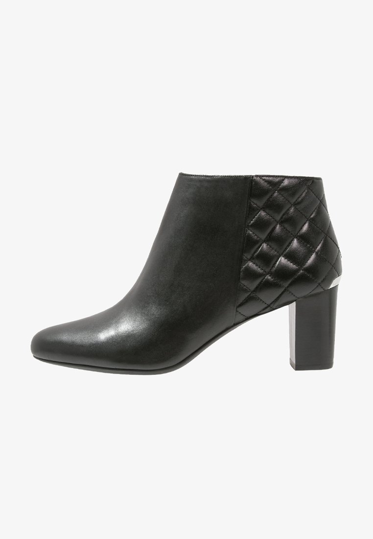 Bottine en cuir noir avec un bout pointu et une texture matelassée sur le côté, dotée d'un talon bloc épais et d'un design épuré.