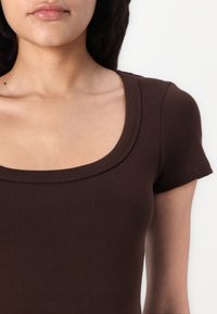 Bruin geribbelde top met een ronde halslijn en korte mouwen, met een soepele textuur en een strakke pasvorm. Geschikt voor casual kleding.