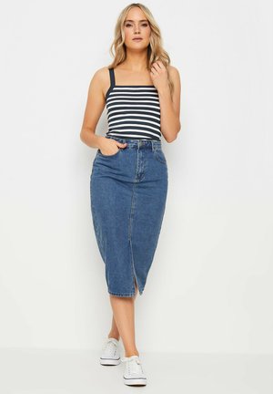 Sininen denim-mittapituinen hame, jossa on edessä halkio, yhdistetty musta-valkoiseen raidoitettuun tiukkaan toppiin. Mallilla on valkoiset tennarit.
