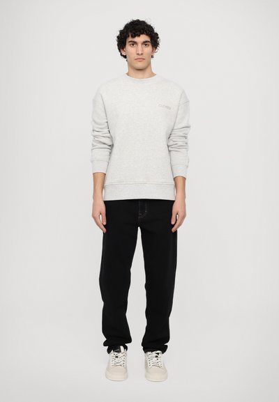 Gray cotton sweatshirt with ribbed cuffs and hem, featuring a small "CLOSED" logo in gold. Paired with black pants and light-colored sneakers.