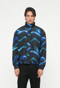 Čierna bunda s modrým vlnitým vzorom, vysoký golier, zapínanie na zips, elastické manžety a lem. Materiál je hladký a ľahký.