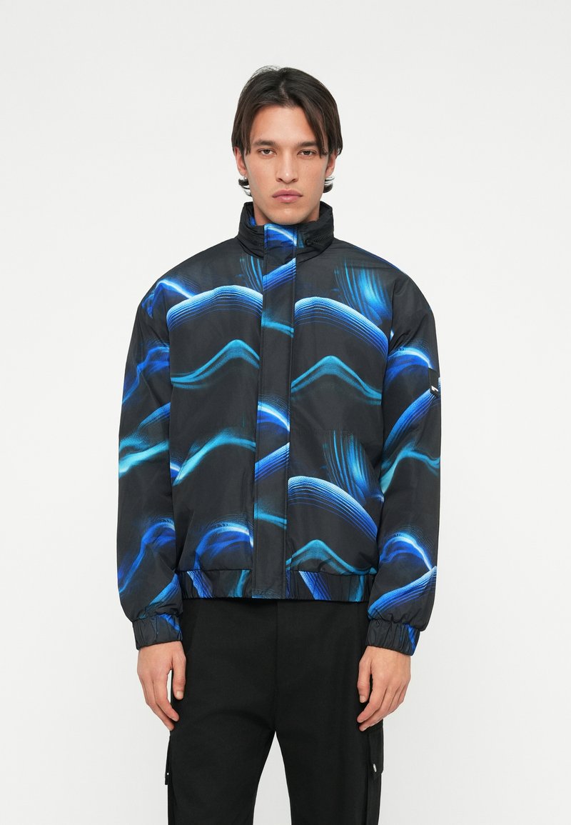 Čierna bunda s modrým vlnitým vzorom, vysoký golier, zapínanie na zips, elastické manžety a lem. Materiál je hladký a ľahký.