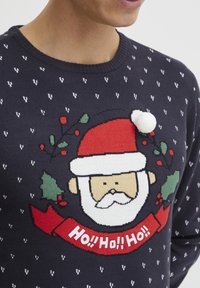Dunkelblauer Strickpullover mit weißen Mustern. Besitzt ein Design mit einem Santa-Gesicht, roten Akzenten und einem flauschigen weißen Pompon auf der Mütze.