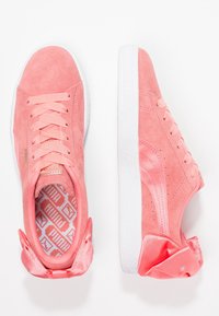 Baskets en daim rose clair avec accents de nœud en satin, lacets plats, semelle en caoutchouc blanche et doublure intérieure à motifs.