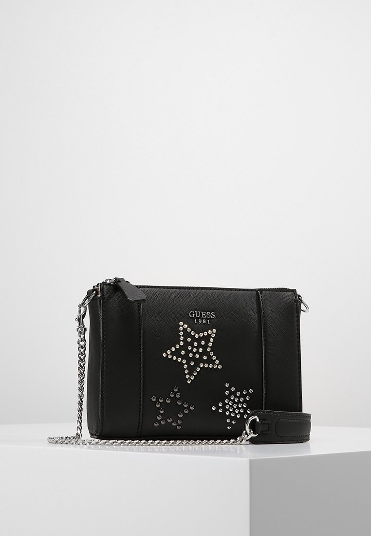 Svart syntetisk handväska med silverkedjeaxelrem, prydd med stjärnmönster dekorerade med rhinestones och en logotyp präglad på framsidan.