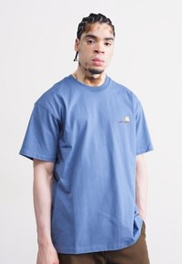 Blauwe katoenen t-shirt met korte mouwen, ronde halslijn en geborduurd logo. Zachte textuur, losse pasvorm en geen zichtbare patronen.