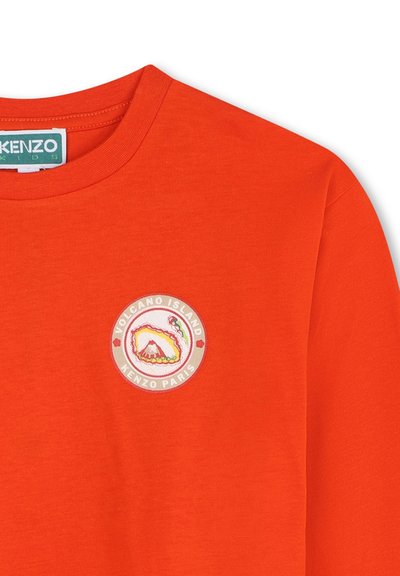 T-shirt in cotone arancione con scollo rotondo, dotato di una toppa ricamata circolare che mostra un vulcano e la scritta "VOLCANO ISLAND KENZO PARIS."