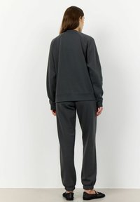 Sweatshirt gris et joggers assortis, fabriqués en tissu doux, avec des poignets et un ourlet côtelés, offrant une coupe décontractée et un design minimal.