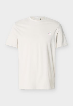 T-shirt blanc uni à manches courtes avec col rond et petit écusson logo CK sur le côté gauche de la poitrine.