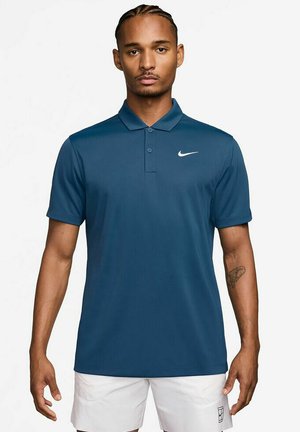 Polo azul marino con una tapeta de tres botones, mangas cortas y un logo blanco de Nike en el lado izquierdo del pecho. Fabricado con una tela atlética suave.