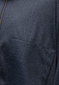 Dark blue textured fabric close-up with a visible zipper on the left and a horizontal seam near the center.