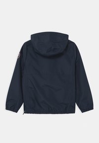 Granatowa, lekka kurtka z kapturem, elastycznymi mankietami i dołem, z okrągłą naszywką z logo na lewym ramieniu. Gładka tekstura.