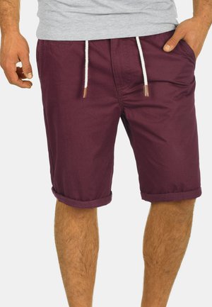 Bordeauxfarbene Shorts aus leichtem Stoff mit einem elastischen Bund, umgeschlagenen Säumen und kontrastierenden weißen Kordelzügen.