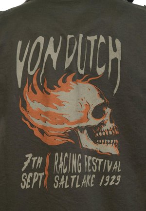 Graphique de crâne enflammé avec le texte "Von Dutch" au-dessus et "7th Sept Racing Festival Salt Lake 1929" en dessous sur un tissu foncé.