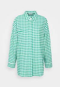 Green and white checkered shirt made of cotton. Features a collar, long sleeves, a front pocket, and a relaxed fit design.
