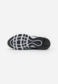 Suela de zapatilla en blanco y negro con un patrón de agarre texturizado, que presenta un acento azul y una forma contorneada para mayor comodidad y soporte.