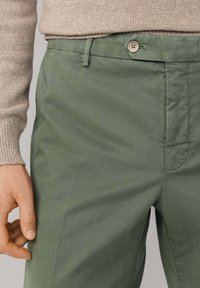 Groene broek van een katoenmix met een gladde textuur, voorzien van een voorsluiting met knopen, zijzakken en een slanke pasvorm.