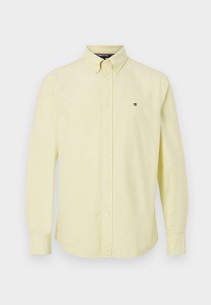 Chemise boutonnée à manches longues jaune clair avec un col classique et un petit logo Tommy Hilfiger sur la poitrine gauche.