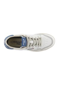 Zapatilla blanca con acentos grises, detalles azules y una superposición texturizada. Presenta una puntera perforada, cordones tradicionales y una etiqueta de marca en la lengua.