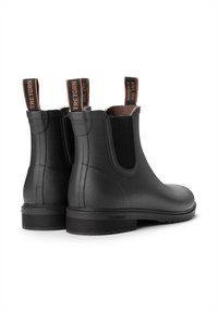 Mustat kumiset Chelsea-kengät elastisilla sivupaneeleilla, vetonauhoilla ylhäällä ja tekstiurilla varustetulla pohjalla. Ominaisuutena sileä matta pinta.