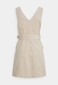 Robe sans manches en velours côtelé beige avec un profond décolleté en V dans le dos, fermeture éclair devant, large ceinture et deux poches latérales à rabat.