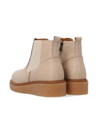 Beżowe skórzane botki za kostkę z elastycznymi bocznymi panelami i teksturowaną, masywn�ą podeszwą. Posiadają uchwyt i kontrastowe tan akcenty.
