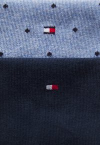 Herrenstrümpfe in Blau und Dunkelmarine. Der blaue Abschnitt weist kleine schwarze Punkte und ein Logo auf; der dunkelmarine Abschnitt zeigt ein kleines Logodetail.