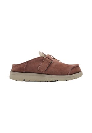 Zapato marrón de ante sin cordones con tira ajustable, suela acolchada y forro de forro polar, diseñado para comodidad y uso informal.