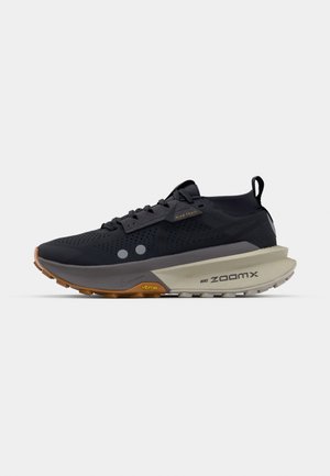 Schwarzer Trailrunningschuh mit perforiertem Obermaterial, grauer Zwischensohle, kontrastierender orangefarbener Außensohle und grauen Akzenten, ausgestattet mit einer Schlaufe am Fersenbereich.
