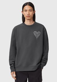 Mørkegrå sweatshirt med rund hals og lange ærmer. Har et design af et dryppende hjerte i lys grå på venstre bryst.