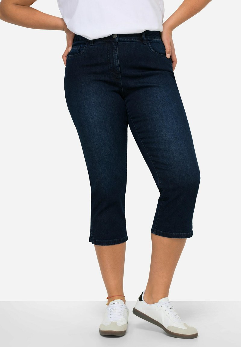 Jeans capri in denim blu scuro con un taglio aderente, vita media e lunghezza cropped, dotati di un classico design a cinque tasche.