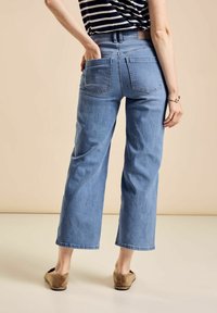 Vaaleansiniset korkeavyötäröiset farkut, joissa on väljä istuvuus, kahdella takataskulla ja suora lahkeiden muoto.