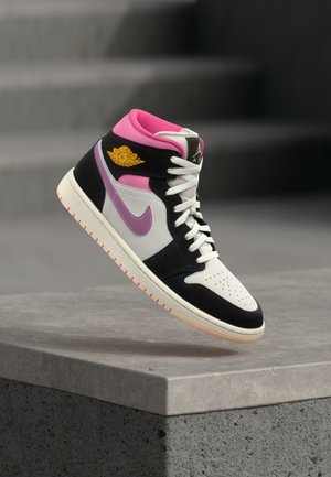 Υψηλός αθλητικός παπούτσι Air Jordan με λευκές, μαύρες, ροζ και μοβ λεπτομέρειες, αιωρούμενος πάνω από ένα γκρι σκυρόδεμα σε ένα μινιμαλιστικό περιβάλλον.