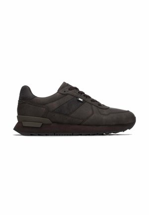 Zapatilla deportiva negra de caña baja con cierre de cordones y suela texturizada, mostrada desde el lado exterior sobre un fondo blanco.