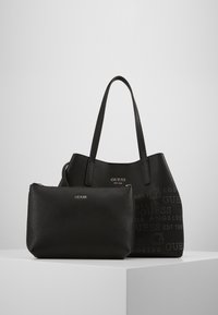 Sort struktureret læder tote taske med prægnet logo og en matchende lynlåspose. Begge har dobbelte håndtag og et elegant design.