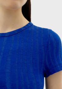 Haut texturé bleu avec un design côtelé, des manches courtes et un col rond, fabriqué à partir d'un tissu léger.