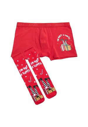Bóxers rojos de algodón con el texto "NO SOY UN SANTA" y regalos navideños; calcetines hasta la rodilla a juego con un diseño similar.