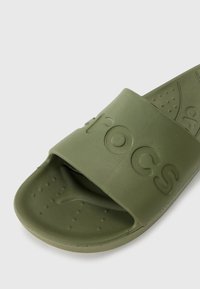 Infradito in gomma verde con una fascia larga che riporta il nome del marchio. La soletta testurizzata presenta piccoli fori di drenaggio. Suola bassa.