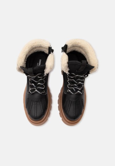 Bottes d'hiver noires avec semelles épaisses marron, lacets blancs et noirs, et doublure douce en polaire crème autour de la cheville.