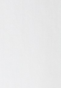 Texture de tissu blanc torsadé avec des crêtes diagonales et une ombre subtile créant un motif doux à la surface.
