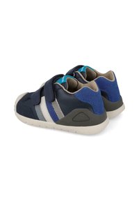 Zapatos infantiles de color azul marino con dos correas de velcro, rayas grises y azules, y un panel trasero texturizado, suela de goma y un interior acolchado.